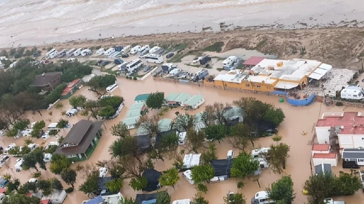 Vista aérea de un campin costero inundado por aguas marrones, con parcelas y autocaravanas anegadas junto al mar.