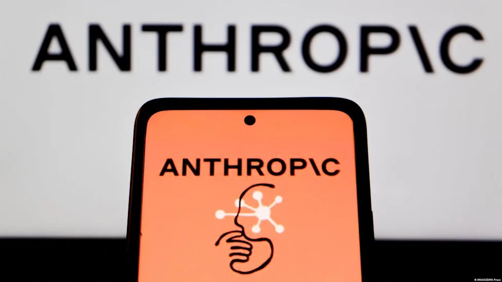 Teléfono móvil mostrando el logo de Anthropic frente a una pantalla con el nombre de la empresa al fondo.